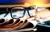 a pair of glasses sitting on a pile of newspapers